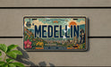 A vintage license plate from Medellín, Colombia, featuring a colorful illustration of the cityscape and landmarks.