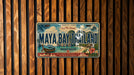 A vintage-style license plate from the island of Maya Bay, Thailand, featuring a tropical landscape with palm trees, a boat, and a beach.