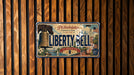 A vintage license plate from Philadelphia, Pennsylvania, with the text "Liberty Bell" and "Let Freedom Ring" printed on it, mounted on a wooden wall.