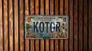 A vintage-style license plate from the island of Kotor, featuring a scenic illustration of the bay and surrounding landscape.