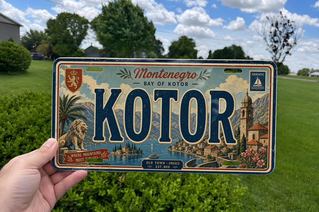 A person is holding a vintage license plate from the town of Kotor, which features a scenic illustration of the town and its surroundings.