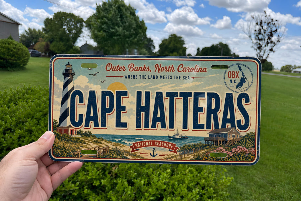 A person is holding a license plate that says "Cape Hatteras" with a lighthouse and beach scene on it.