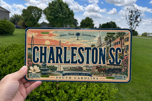 A person is holding a license plate with the text "CHARLESTON SC" on it, which is a historic charm of Lowcountry South Carolina.