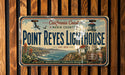 A vintage California Coast lighthouse license plate with a scenic coastal landscape and a bird flying over the lighthouse.