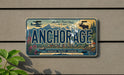 A vintage license plate with the word "ANCHORAGE" prominently displayed, featuring a scenic mountain landscape and a moose.