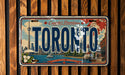 A vintage license plate from Toronto, Canada, featuring a cityscape and iconic landmarks such as the CN Tower.