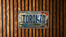 A vintage Toronto license plate is displayed against a wooden background.