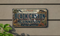 A vintage license plate with the text "Black Canyon of the Gunnison" and a scenic illustration of the area.