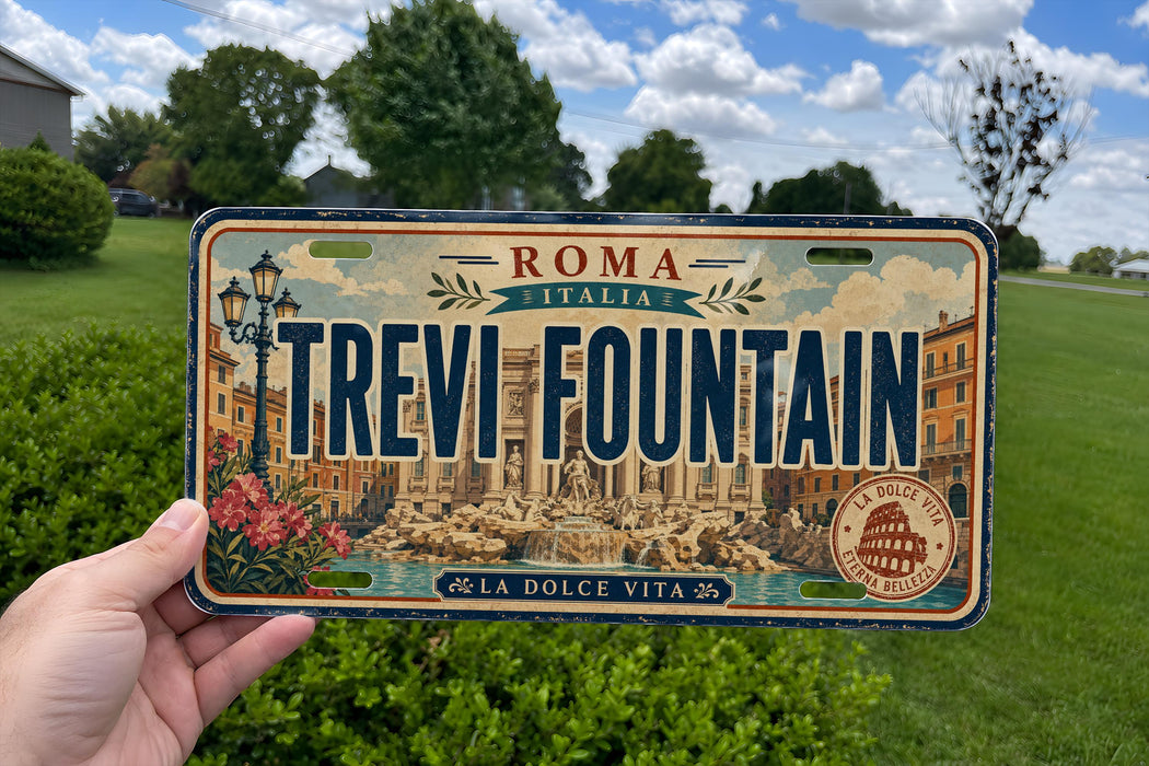 A person is holding a license plate that says "Roma Italy Trevi Fountain" with a cityscape and fountain image on it.