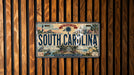 A license plate from South Carolina is displayed on a wooden wall.