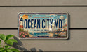 A license plate with the text "OCEAN CITY MD" and an illustration of a beach and lighthouse, mounted on a wall.
