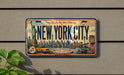 A vintage-style license plate with the text "NEW YORK CITY" and various iconic landmarks and symbols, such as the Statue of Liberty, the Empire State Building, and Broadway, is displayed on a wall.