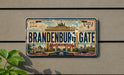 A vintage-style license plate with the text "Brandenburg Gate" and "Berlin Germany" printed on it, mounted on a wall.