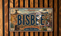 The image is a license plate from Arizona, featuring the word " Bisbee" prominently displayed. The plate also includes various illustrations and text elements related to the state of Arizona, such as the location "Cochise County" and the phrase "Queen of the Copper Camps".