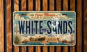 A vintage-style license plate from New Mexico, featuring the text "WHITE SAND" and the state's name.