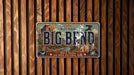 A vintage-style license plate with the text "BIG BEND" and "Wild & Scenic" printed on it, mounted on a wooden wall.