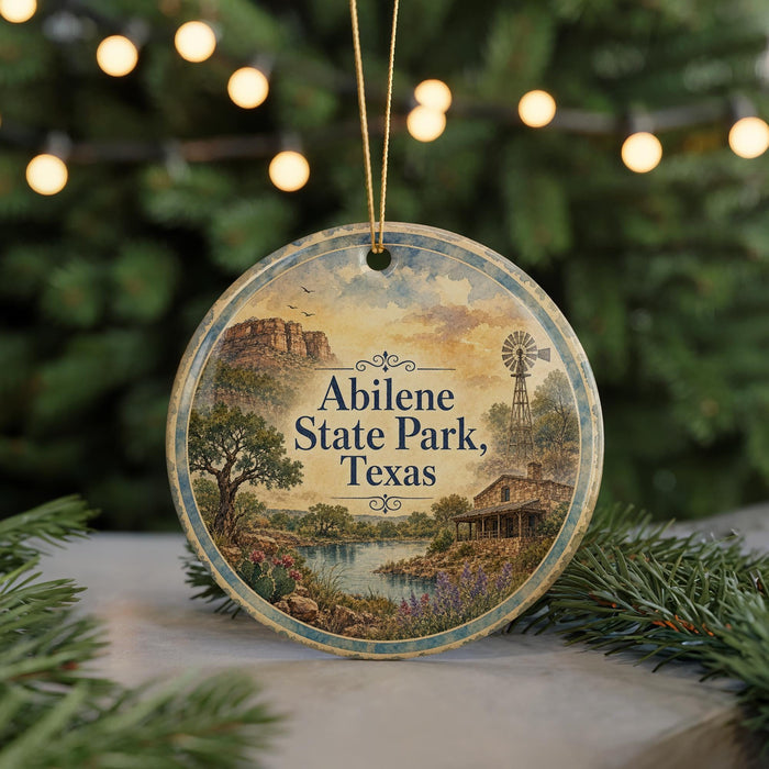 A round ornament with a painting of Abilene State Park, Texas, featuring a scenic landscape with a windmill, trees, and a river.