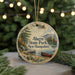 A round ornament with a scenic image of a lake and mountains, featuring a canoe, is hanging from a string.