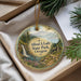 A round ornament with a scenic landscape of a waterfall, mountains, and a cabin, hanging from a string.