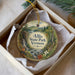 A decorative ornament in a box, featuring a scenic landscape with a waterfall, trees, and a path leading to a lake.