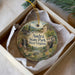 A decorative ornament in a box, featuring a scenic landscape with a waterfall, a house, and greenery.