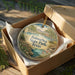 A circular ornament with a scenic landscape of Balmorheeta State Park, Texas, displayed in a wooden box with a gold string.