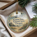 A round ornament with a scenic landscape of a lighthouse, mountains, and a beach, hanging from a string.
