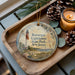 A decorative ornament featuring a lighthouse and the text "Barnes Lighthouse State Park, New Jersey" is displayed on a wooden tray, accompanied by pine cones and a lit candle.