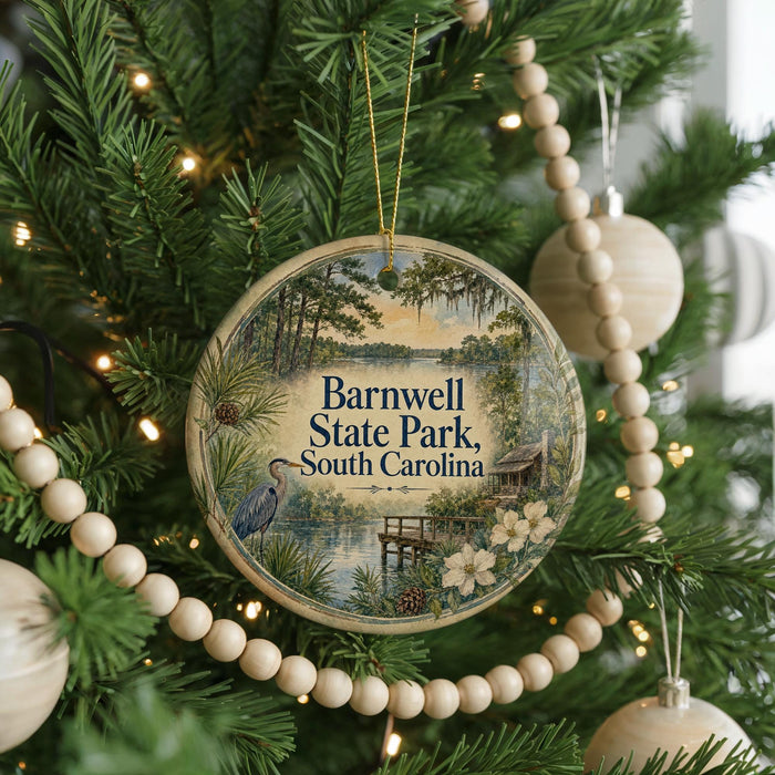 A round ornament hanging on a Christmas tree, featuring a scenic image of Barnwell State Park in South Carolina.