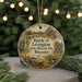 A round ornament with a painting of a historical battle scene, featuring a cannon, soldiers, and buildings, hanging on a string.