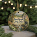 A round ornament featuring a scenic landscape with a bear, trees, and a stream, hanging from a string.