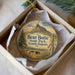 A decorative ornament in a box, featuring a scenic landscape with a mountain and wildlife, including bison.