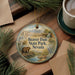 A round ornament with a painting of a beaver in Beaver Dam State Park, Nevada, is displayed on a wooden surface alongside a cup of coffee and some pine branches.