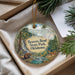 A round ornament with a forest scene and a bear, hanging from a string.