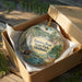 A wooden box containing a decorative ornament with a scenic landscape of Beavers Bend State Park, Oklahoma.