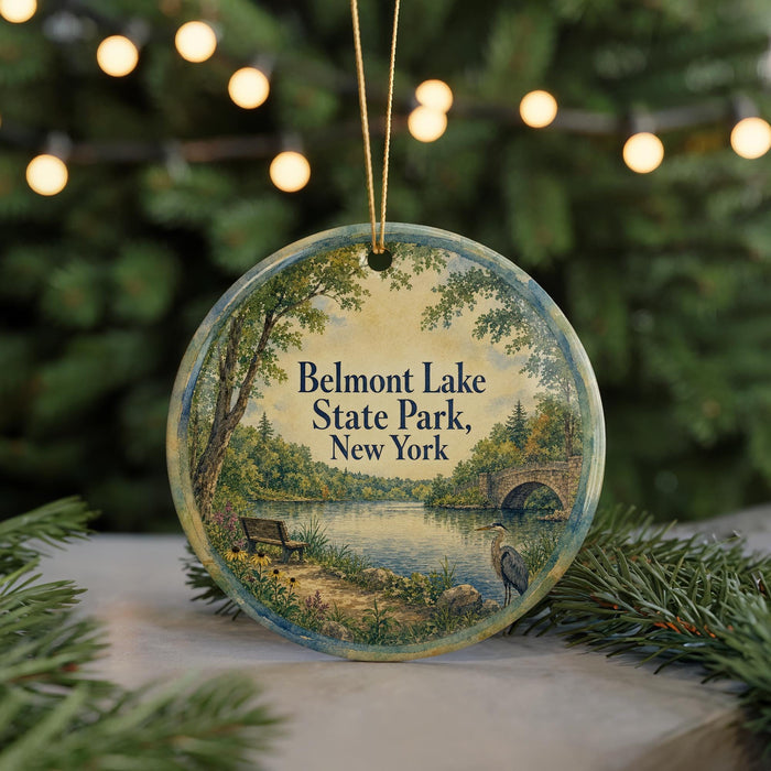 A round ornament with a painting of Belmont Lake State Park, New York, featuring a bench, a bird, and a bridge.
