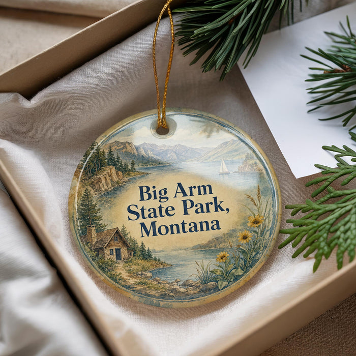 A decorative ornament with a scenic landscape of Big Arm State Park, Montana, featuring a cabin and mountains in the background.