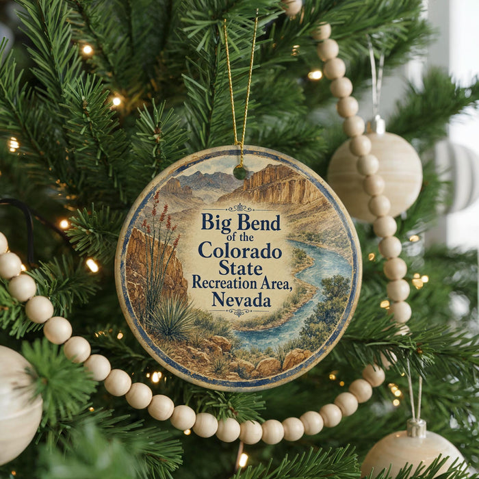 A round ornament hanging on a Christmas tree, featuring a scenic image of the Big Bend of the Colorado State Recreation Area, Nevada.