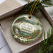 A decorative ornament in a box, featuring a scenic landscape with a waterfall and pine trees, with the text "Big Ridge State Park, Tennessee" printed on it.