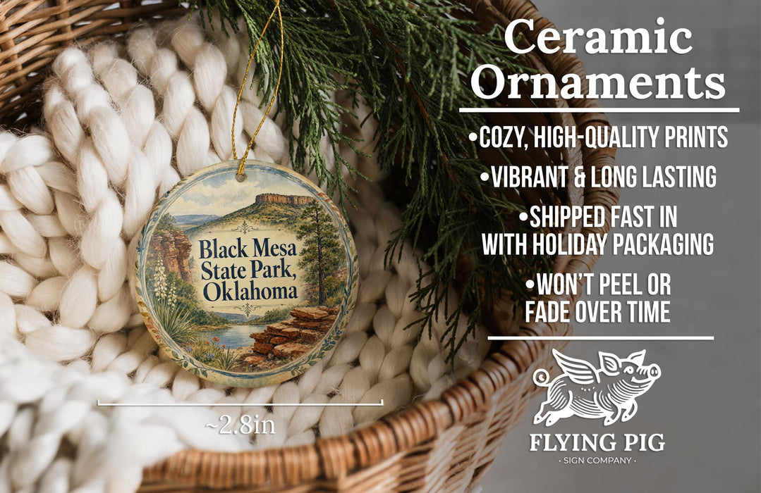 Ceramic ornaments, featuring a design of Black Mesa State Park, Oklahoma, hanging in a basket with pine branches.