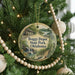 A circular ornament hanging on a Christmas tree, featuring an illustration of a train and a scenic landscape.