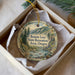 A decorative ornament in a box, featuring a scenic landscape with mountains, trees, and a river.