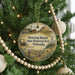 A round ornament hanging on a Christmas tree, featuring an illustration of a historical site and a wagon.