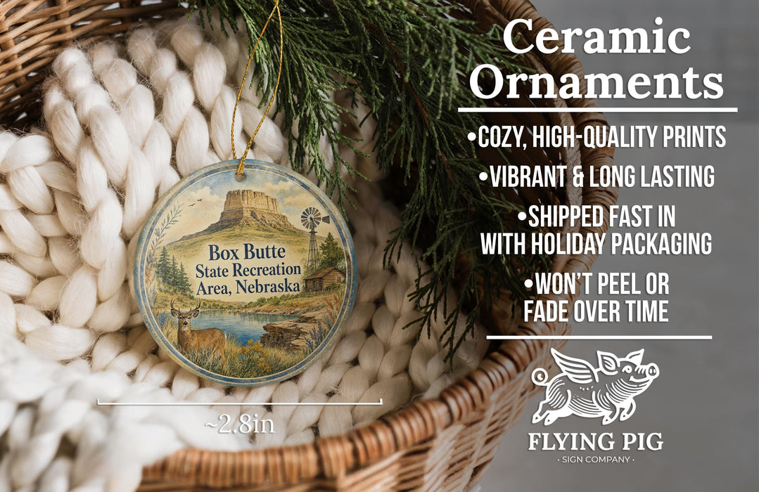 Ceramic ornaments, featuring a detailed image of Box Butte State Recreation Area, Nebraska, with a wicker basket and greenery in the background.
