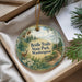 A decorative ornament with a scenic image of a forest and a deer, hanging from a string.