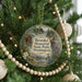 A round ornament hanging on a Christmas tree, featuring a scenic landscape with a cabin, trees, and wildlife.