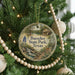 A round ornament on a Christmas tree, featuring a scenic image of Buescher State Park, Texas, with a deer and a waterfall.