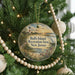 A round ornament hanging on a Christmas tree, featuring a lighthouse and a scenic landscape.