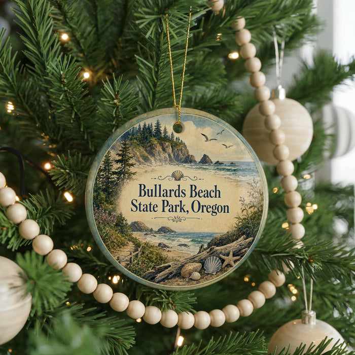 A round ornament hanging on a Christmas tree, featuring a scenic landscape with a beach, mountains, and a body of water.