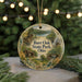 A decorative ornament featuring a scenic landscape with a cabin, trees, and a lake, hanging from a string.